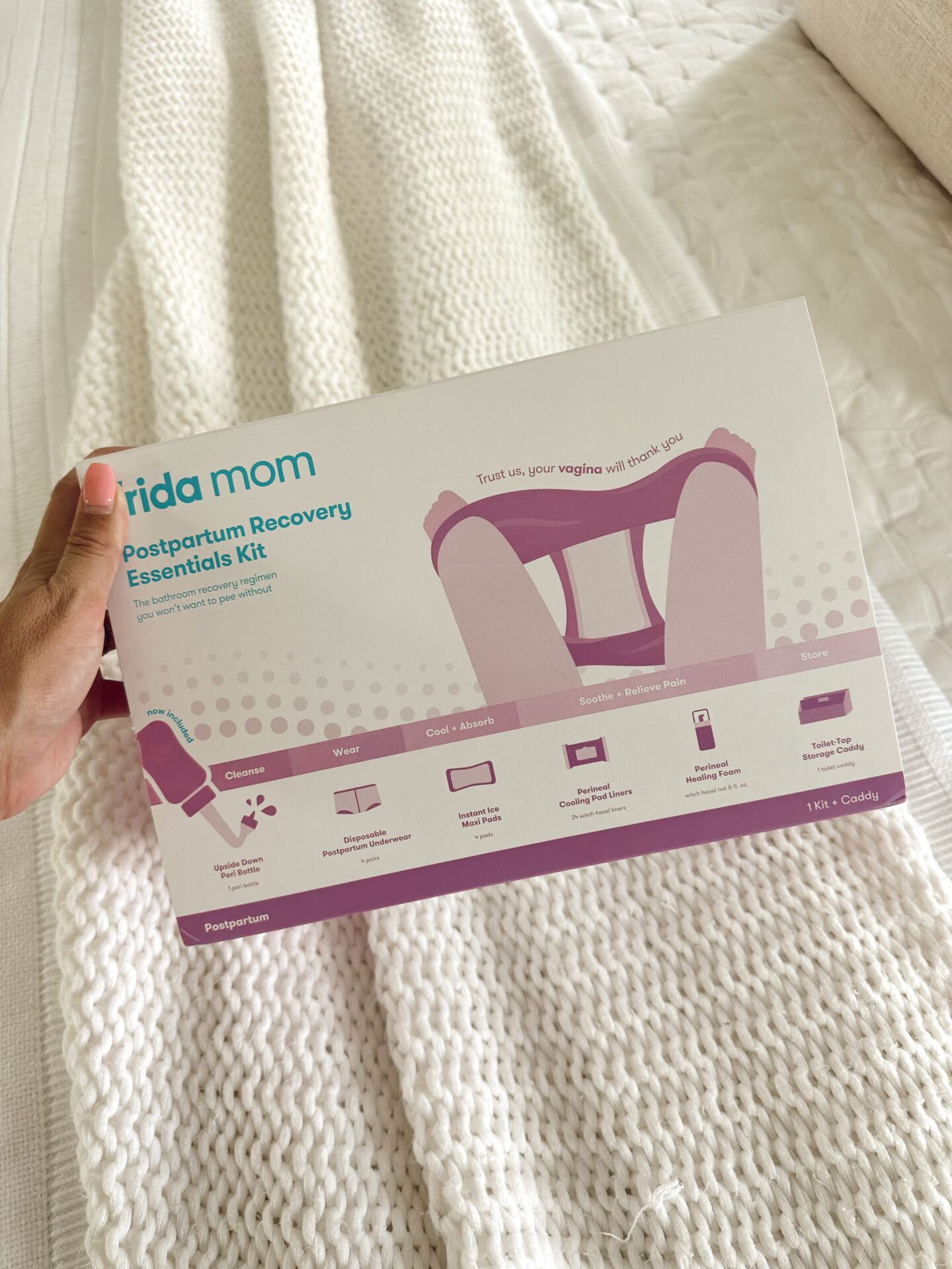 Frida Mom Postpartum Recovery Essentials Kit box on a white knit blanket