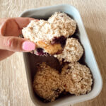 Close-up of a sourdough discard blueberry muffin with crumb topping, held in hand.